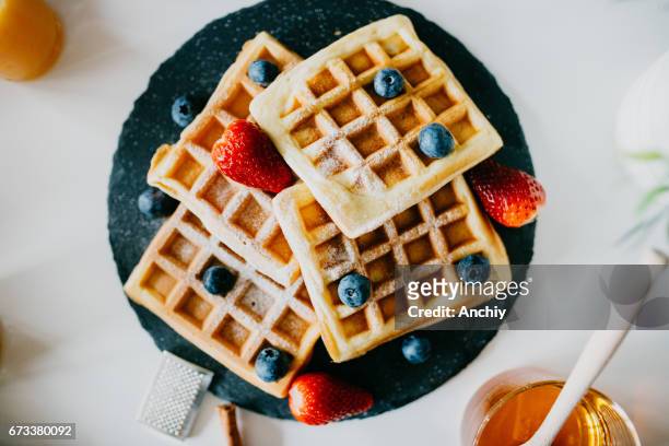waffles with blueberries, strawberries and powdered sugar - waffles stock pictures, royalty-free photos & images