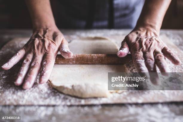 handen bakken deeg met de deegroller op houten tafel - roll up stockfoto's en -beelden