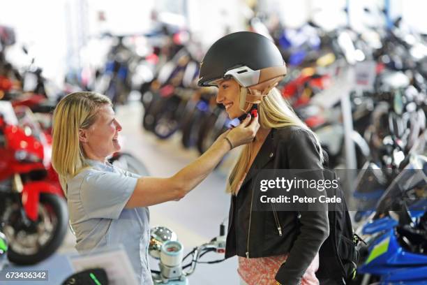 young woman buying helmet in motorbike showroom - women black and white motorcycle fotografías e imágenes de stock