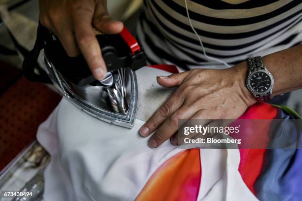 An employee irons a dress at the Ferrara Manufacturing Co. Clothing factory in the Garment District of New York, U.S., on Monday, April 10, 2017....
