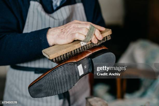 zapatero de viejo está puliendo un zapato - zapatos fotografías e imágenes de stock