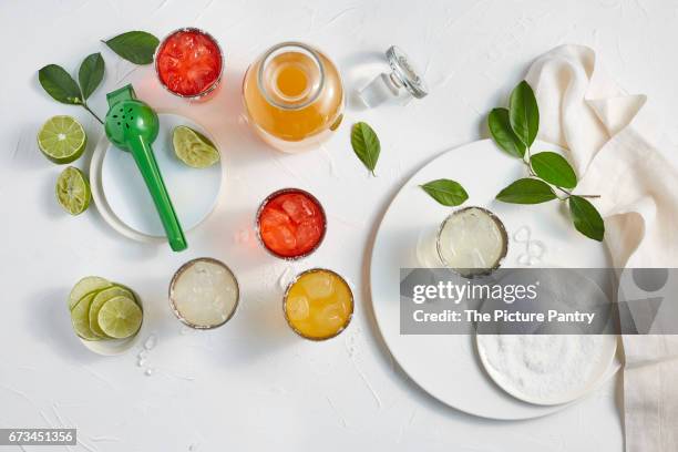 assorted flavors of margaritas in glasses on a white surface with salt and limes - pomegranate margarita stock pictures, royalty-free photos & images