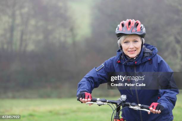 older woman outside with bike on grey day - cycling helmet stock pictures, royalty-free photos & images