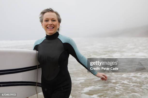 older woman running out of sea with surfboard - stronger 2017 film stock-fotos und bilder