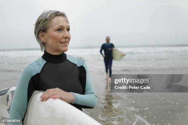 older couple on beach with surfboards - man surfing photos et images de collection