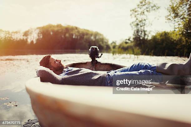 Serene man laying relaxing in canoe on sunny lake