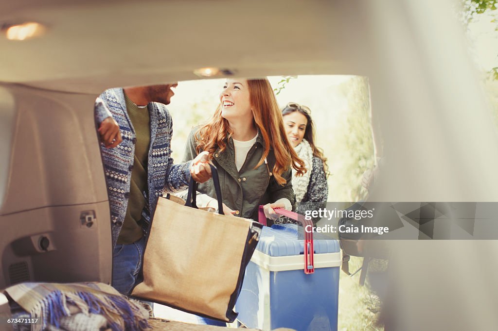 Smiling friends unloading back of car