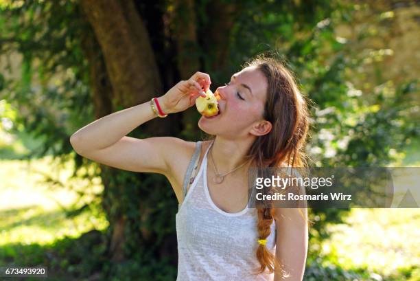 young woman eating an apple - pomme croquée photos et images de collection