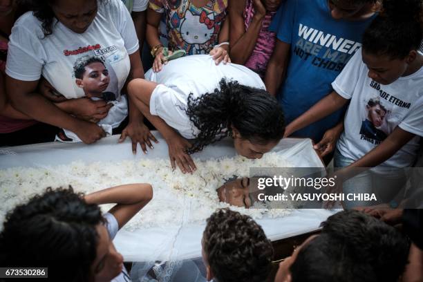 Family and friends cry beside the coffin of 13-year-old Paulo Henrique de Oliveira, who was killed by a stray bullet during a police operation...