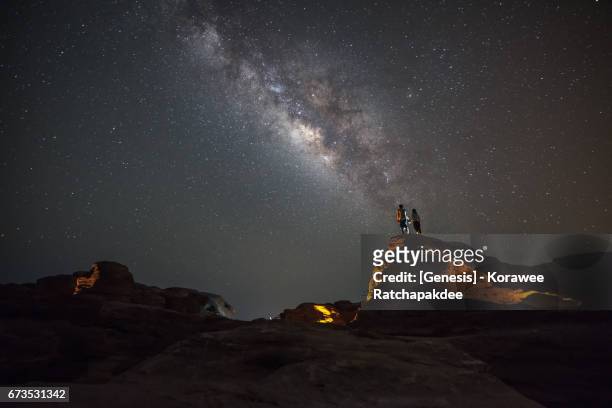 a couples standing on the rock along with a beautiful milky way in the sky - mann ganzkörper lachen stehen stock-fotos und bilder