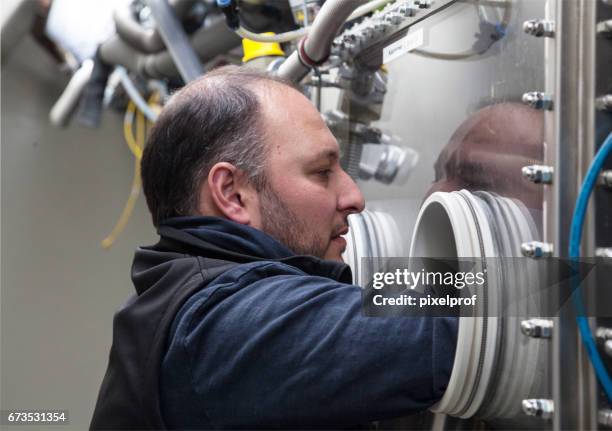 scientist in lab testing materials in glove box - glove box stock pictures, royalty-free photos & images