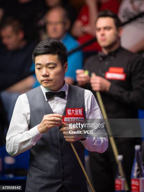 Ding Junhui of China chalks the cue during his quarter final match against Ronnie O'Sullivan of England on day twelve of Betfred World Championship...