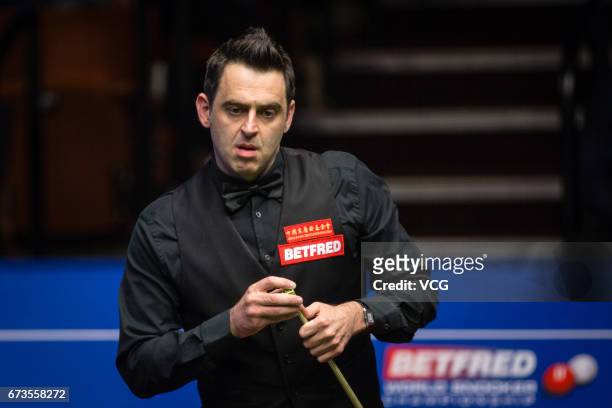 Ronnie O'Sullivan of England chalks the cue during his quarter final match against Ding Junhui of China on day twelve of Betfred World Championship...