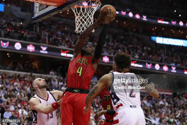Paul Millsap of the Atlanta Hawks puts up a shot between Marcin Gortat and Kelly Oubre Jr. #12 of the Washington Wizards in the second half in Game...