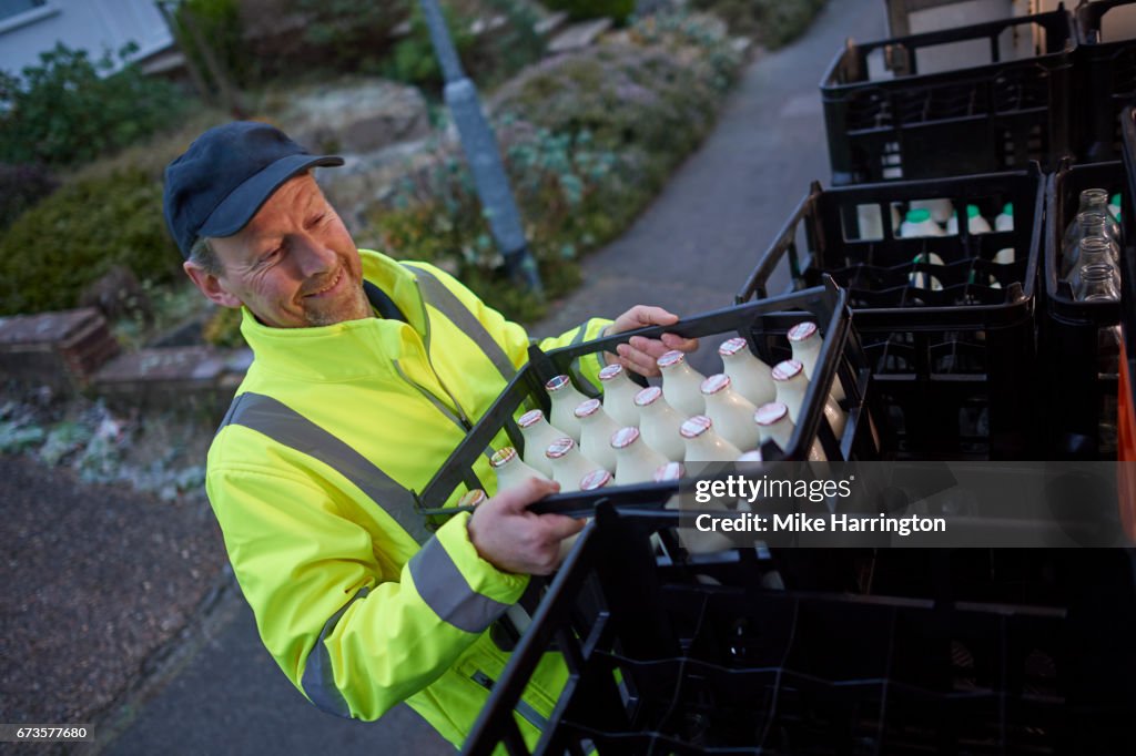 Milkman unloading his milk float in early morning