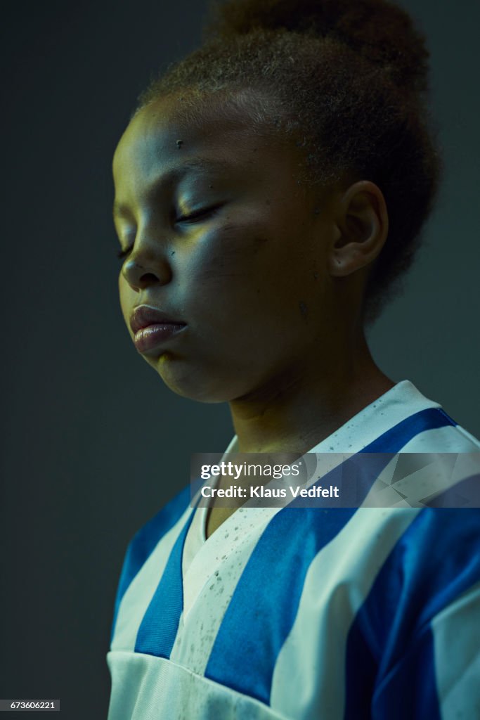 Young female football player with closed eyes