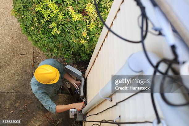 elevated view of cable installer working on house access point - cable installer stock pictures, royalty-free photos & images