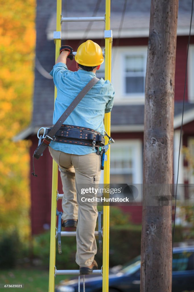 Lineman climbing ladder at power pole