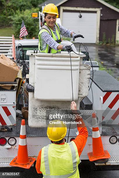 hispanic female cable lineman stringing a new line - cherry picker stock pictures, royalty-free photos & images