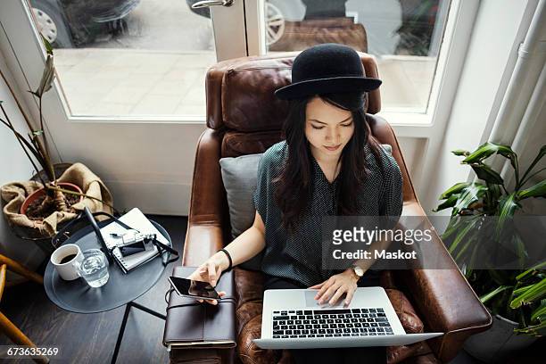high angle view of creative businesswoman working while sitting on chair - sitting at a laptop with facebook stock pictures, royalty-free photos & images
