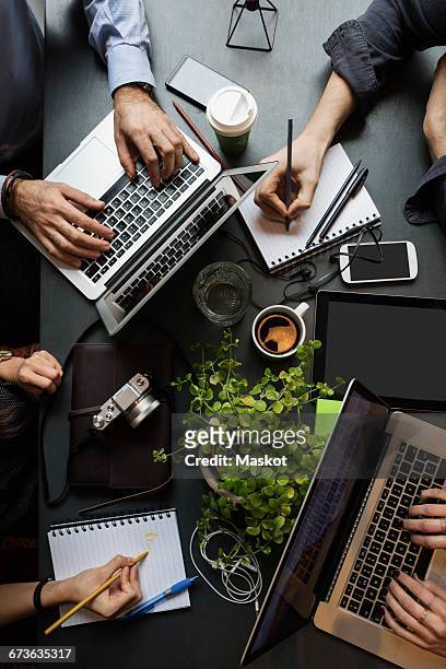 directly above shot of business team working at table in creative office - four bussines man at office imagens e fotografias de stock