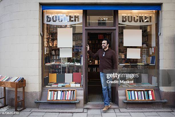 male librarian looking away while standing at doorway - bookshop stock pictures, royalty-free photos & images