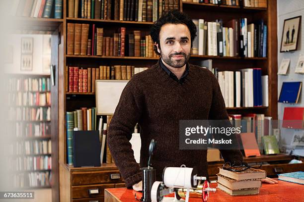 portrait of smiling librarian standing against bookshelves - bibliotecário imagens e fotografias de stock