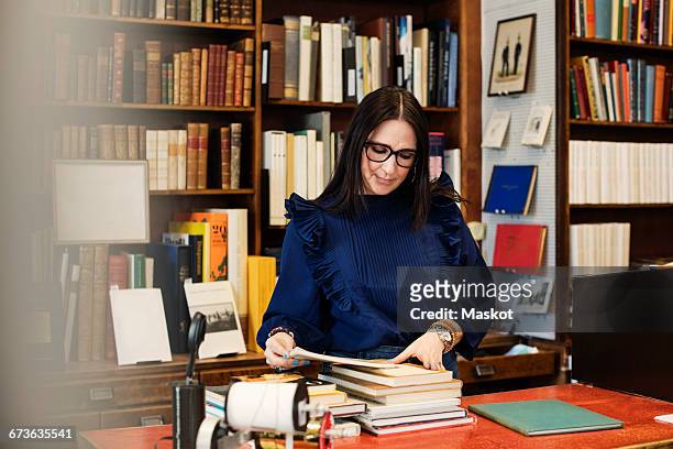 female librarian looking at books in bookstore - librarian stock pictures, royalty-free photos & images