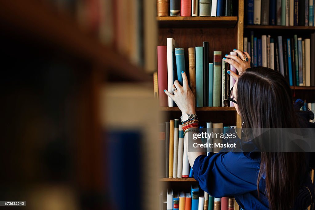 Rear view of woman searching book in library