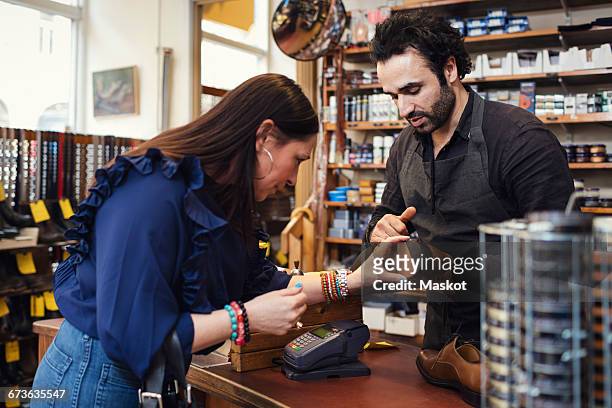 shoemaker showing shoe to female customer in store - shoe repair stock-fotos und bilder