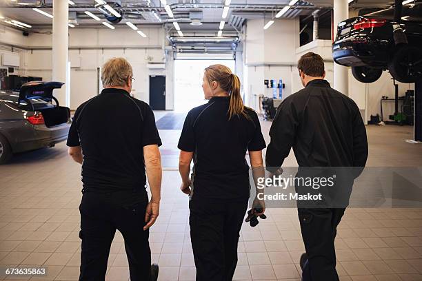 rear view of team walking in auto repair shop - senior blaumann stock-fotos und bilder