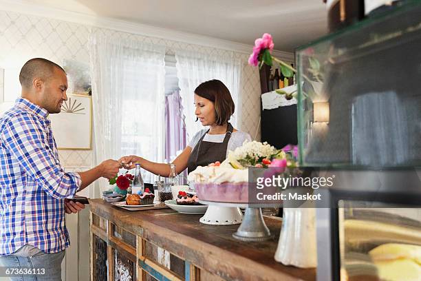 customer giving credit card to female owner at cafe counter - customer profile stock pictures, royalty-free photos & images