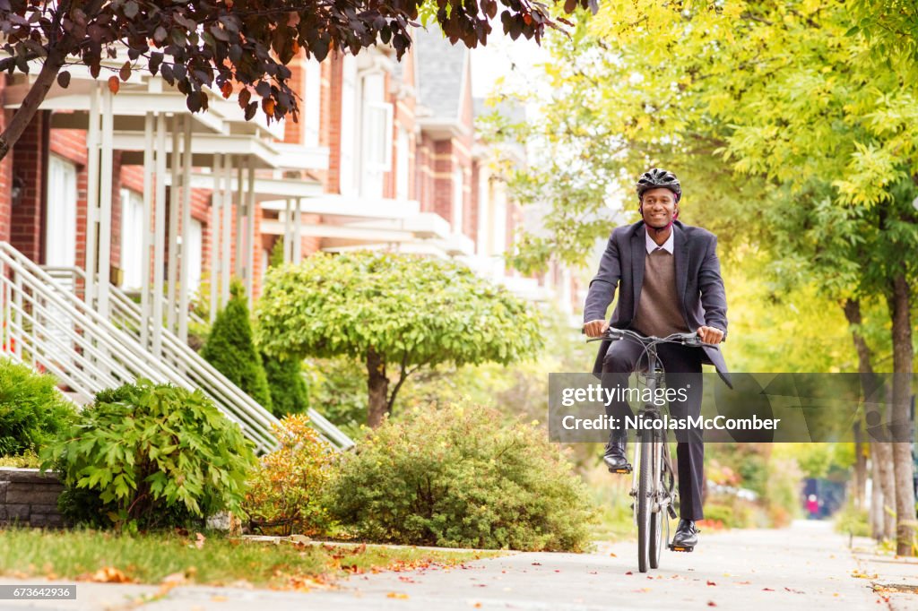 Single black male in his 30s cycling on urban sidewalk in Autumn