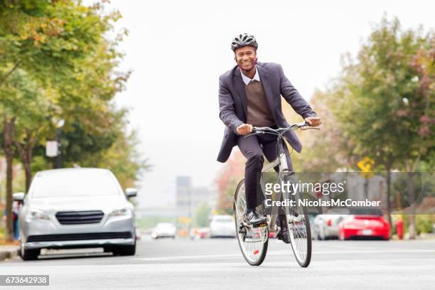 single black male in his 30s smiling while commuting to work by bicycle - commuter cyclist stock pictures, royalty-free photos & images
