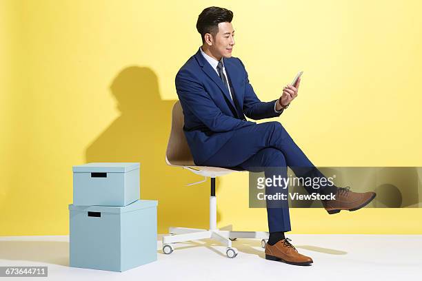 young business man looking at mobile phone - cross legged stock pictures, royalty-free photos & images
