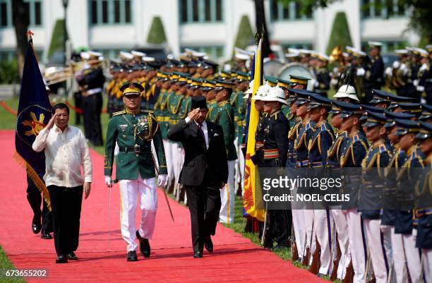 Philippine President Rodrigo Duterte and Brunei's Sultan Hassanal Bolkiah salute as they walk past a guard of honour during a welcoming ceremony at...