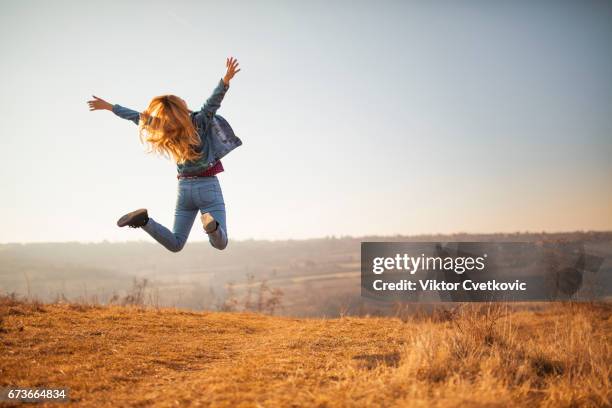 cheerful woman jumping in the park - natural shot female stock pictures, royalty-free photos & images