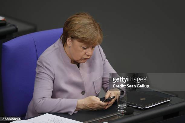 German Chancellor Angela Merkel types on a Blackberry mobile phone after she gave a government declaration outlining Germany's position on...