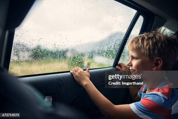 little boy travelling in car on a rainy day - car rain stock pictures, royalty-free photos & images