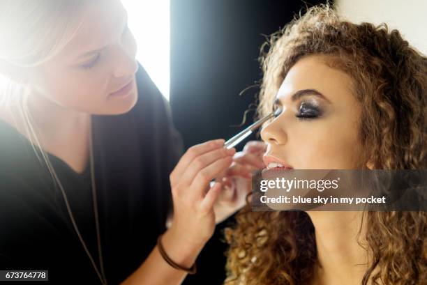 a make-up artist working on a model. - makeup artist stock pictures, royalty-free photos & images