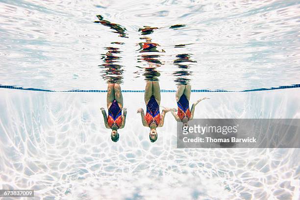 synchronized swimmers treading water upside down - natación sincronizada fotografías e imágenes de stock