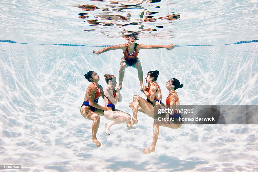 Synchronized swim team preparing to perform lift