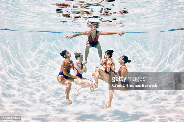 synchronized swim team preparing to perform lift - match sport stockfoto's en -beelden