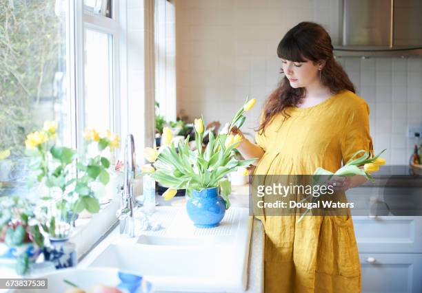 prenant woman putting spring flowers in vase at home. - flowers vase ストックフォトと画像