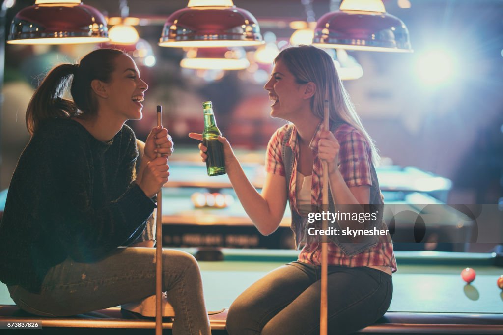 Vrolijke vrouwen praten over iets grappig in een zwembad hal.