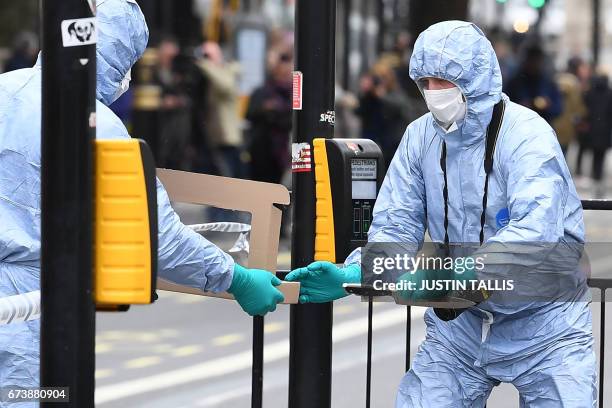 British police forensics officer passes a knife to a colleague as they collect evidence on Whitehall near the Houses of Parliament in central London...