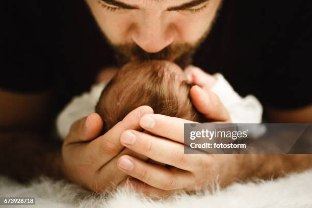 father kissing his newborn baby girl - baby head in hands stock pictures, royalty-free photos & images