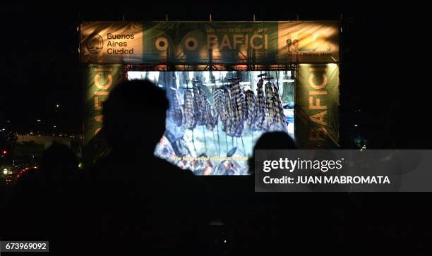Spectators watch the Argentine movie "Todo sobre el Asado" sitting on the grass in Francia square in Buenos Aires on April 24 during its projection...