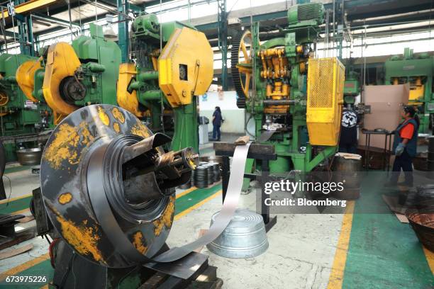 Strips of pewter move through a press machine at the Baro Industrial SA manufacturing facility in the Azcapotzalco neighborhood of Mexico City,...