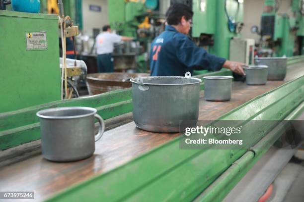 Pewter cookware moves down a conveyor belt during the enamel process at the Baro Industrial SA manufacturing facility in the Azcapotzalco...